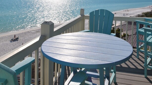 Un terrazzo con un tavolo rotondo e sedie, affacciato su una spiaggia e vista libera sull'oceano.