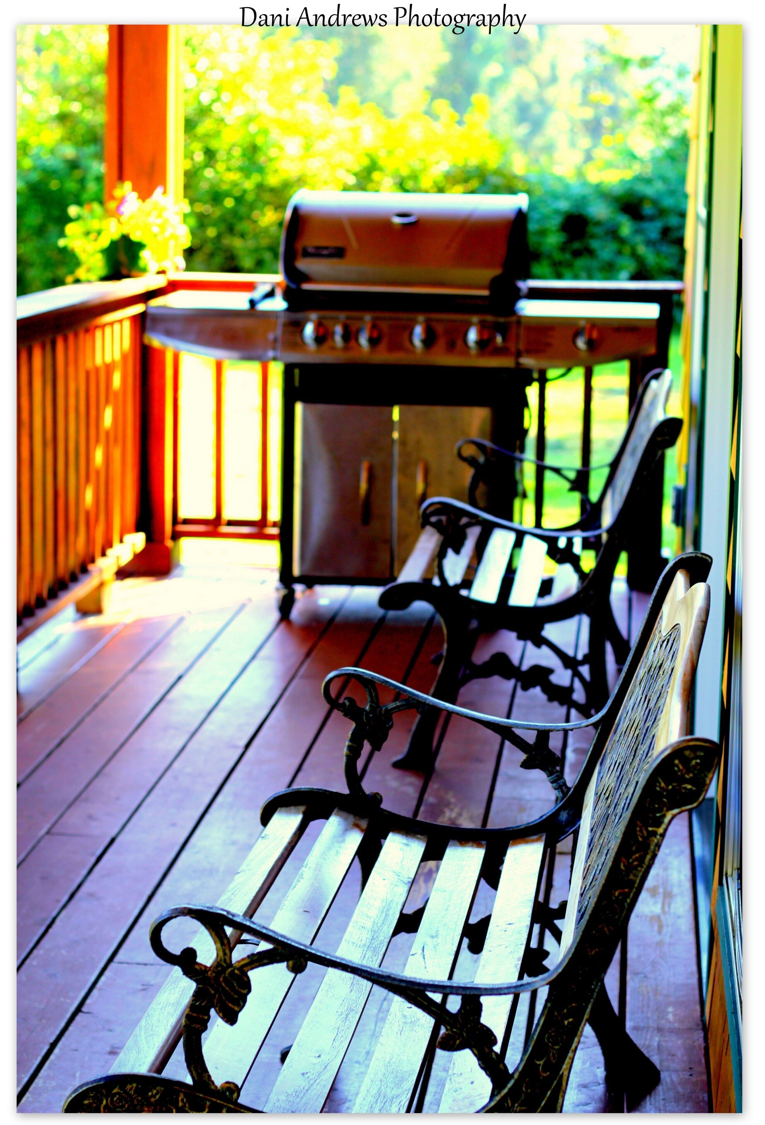 A wooden deck with a grill and two metal benches.