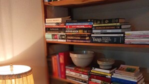 Une bibliothèque remplie de livres et de bols, une lampe et une petite table sur laquelle se trouve un vase.