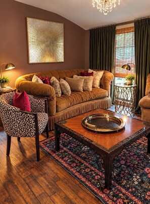 A living room with a brown sofa, a leopard print chair, a wooden coffee table, and a patterned rug. - SERENE SMALL HOUSE ON POND WITH FOUNTAIN (Kennard)