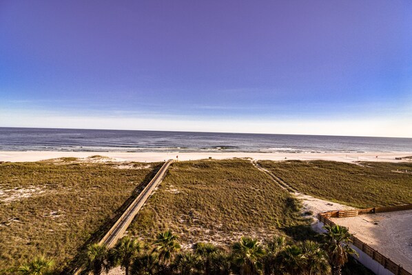 A coastal landscape with a beach, a dirt path, and a wooden fence. - Tidewater 507 - Gulf Front Unit updated (Orange Beach)