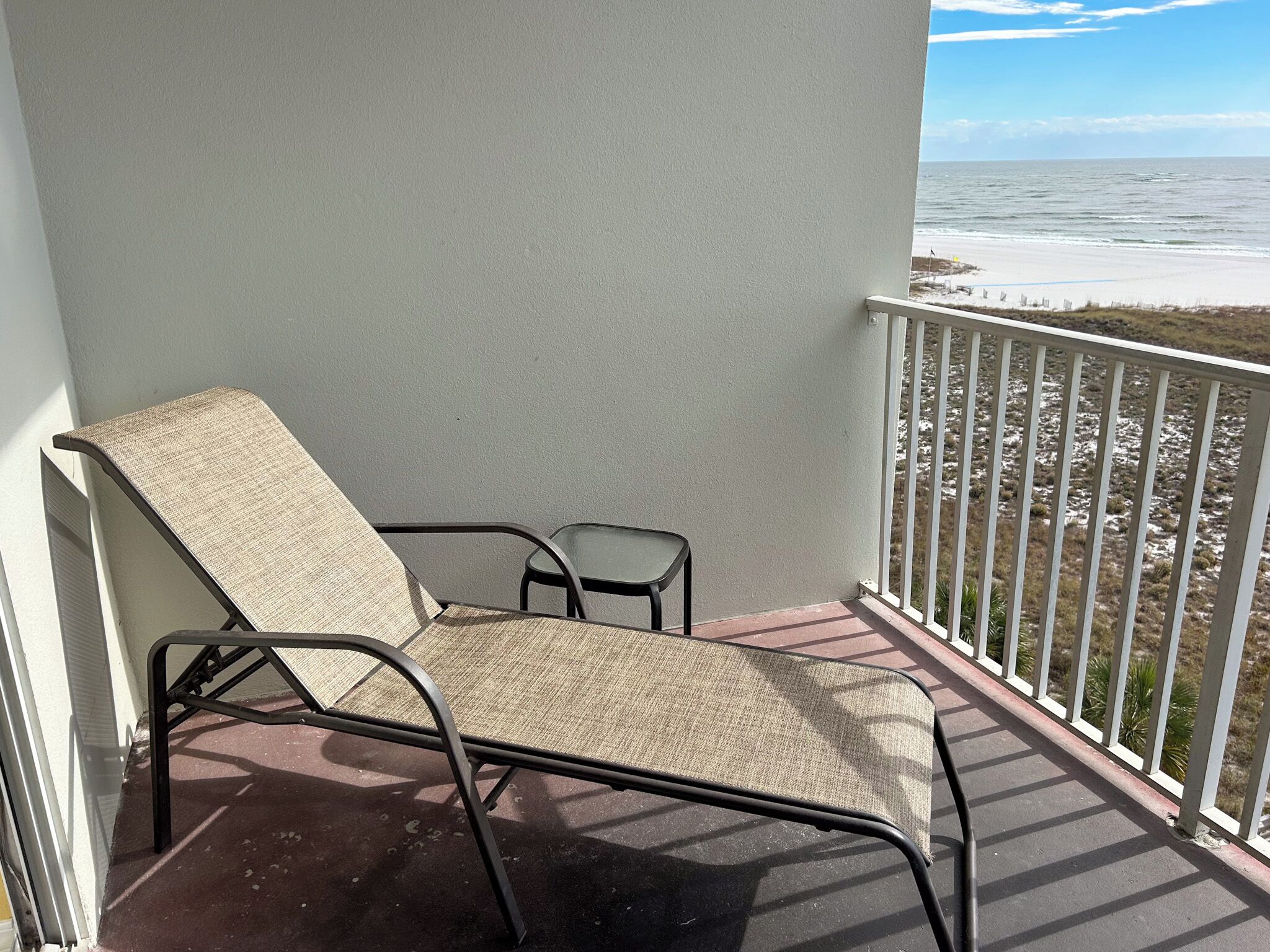Un balcone con due sedie e una ringhiera, vista sulla spiaggia.