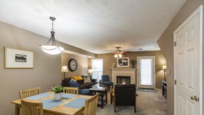 A living room with a dining table, chairs, a sofa, a fireplace, and a ceiling fan. - 3 Bedroom Downtown Townhouse, Close to All!  (Lexington)