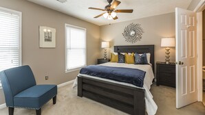 A bedroom with a bed, bedside tables, a chair, a ceiling fan, and a decorative wall piece. - 3 Bedroom Downtown Townhouse, Close to All!  (Lexington)