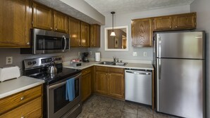 A kitchen with wooden cabinets, stainless steel appliances, a dishwasher, and a tiled floor. - 3 Bedroom Downtown Townhouse, Close to All!  (Lexington)