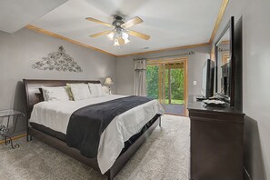 A bedroom with a bed, a ceiling fan, a dresser, a mirror, and a view of the outdoors. - 6 Bedroom w/ Fireplace, Hot Tub, Pool Table, Foosball, and fire pit (Galena)