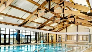 En indendørs swimmingpool med højt til loftet og store vinduer.