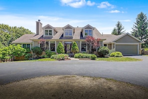 A two-story house with a garage, a front porch, and a driveway. - 6 Bedroom w/ Fireplace, Hot Tub, Pool Table, Foosball, and fire pit (Galena)