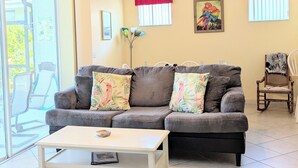 A living room with a grey sofa, a white coffee table, and a ceiling fan. - Kid Friendly Home W/Pool  in Gated Community,10 Min. to Disney (Kissimmee)
