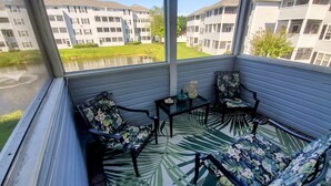 Un balcon avec deux chaises, une petite table et une statue d’ange décorative.