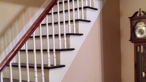 Eine Holztreppe mit weißen Spindeln und dunklen Stufen, die zu einer Zwischenebene mit Holzboden führt.