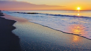 Una playa al atardecer, con olas lamiendo suavemente la orilla.