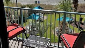 Un balcón con vistas a la playa, mobiliario exterior y zona de piscina.