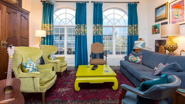 A living room with a yellow coffee table, green armchairs, a blue sofa, and a patterned rug. - Artistic Loft close to Lake Michigan beaches, craft breweries & outlet shopping (Michigan City)