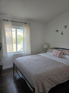 A bedroom with a bed, curtains, a nightstand, a lamp, and wall art. - Hillside at Emigrant Creek Ranch (Ashland)