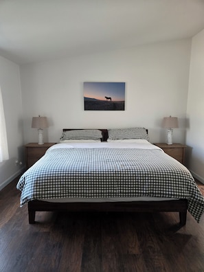 A bedroom with a large bed, two bedside tables with lamps, a wall-mounted picture, and wooden flooring. - Hillside at Emigrant Creek Ranch (Ashland)