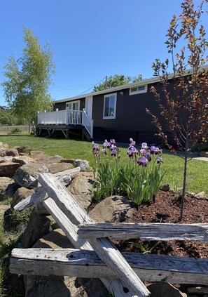 A house with a porch, a small tree, and purple flowers in the yard. - Hillside at Emigrant Creek Ranch (Ashland)