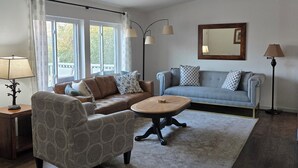 A living room with a brown sofa, a patterned armchair, a round coffee table, and a floor lamp.