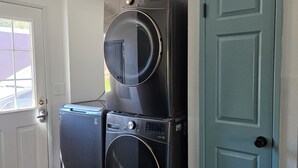 A laundry room with two stacked washers and dryers, a door, and a window.