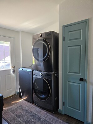 A laundry room with two stacked washers and dryers, a door, and a window. - Hillside at Emigrant Creek Ranch (Ashland)