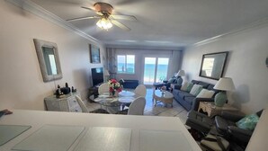 A spacious living area with a dining table, a sofa, and a balcony with a view.