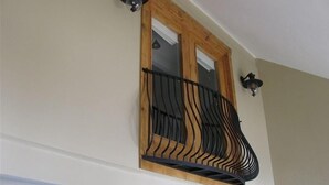 A balcony with a wooden frame and black metal railing, attached to a beige wall with two wall-mounted light fixtures. - 3 Bedroom Condo,  Great Location for Ski Families to Super Bee Lift (Copper Mountain)