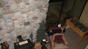 A stone fireplace, a sofa, a small Christmas tree, and a foosball table in a room with a glass door. - 3 Bedroom Condo,  Great Location for Ski Families to Super Bee Lift (Copper Mountain)