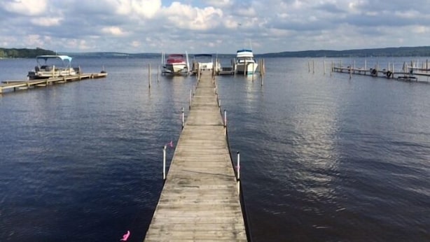 A wooden pier extending into calm water with boats docked at the end.