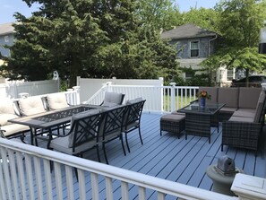 A deck with outdoor furniture, including a table and chairs, surrounded by a white fence. - Luxurious Beach House, 5 min walk to the Casino, beach and Boardwalk (Atlantic City)