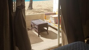 Une chambre avec vue sur la plage, une petite table et un banc à l’extérieur.