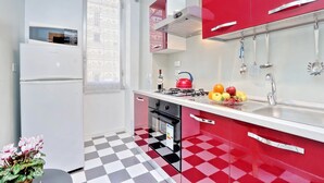 A kitchen with a refrigerator, oven, and a red and white color scheme. - Rome Colosseum Vacation Rental - Spacious Apartment Ancient Rome 3BR/2B Wi-Fi (Roma)