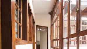 A narrow hallway with wooden floors and large windows.