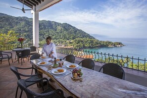 A chef preparing food on a terrace with a scenic view of the sea and hills. - Ocean View Puerto Vallarta Villa Overlooking Mismaloya Beach (Lomas de mismaloya)
