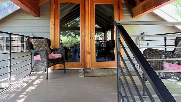 A covered outdoor area with a wooden ceiling and a glass door leading inside.