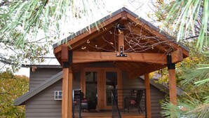 A wooden cabin with a porch, a staircase, and a covered area with chairs.