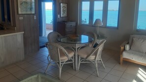 A room with a glass table surrounded by wicker chairs, a white sofa, and large windows overlooking the sea. - Centrally located - Gorgeous view of Elizabeth Harbour  (George Town)