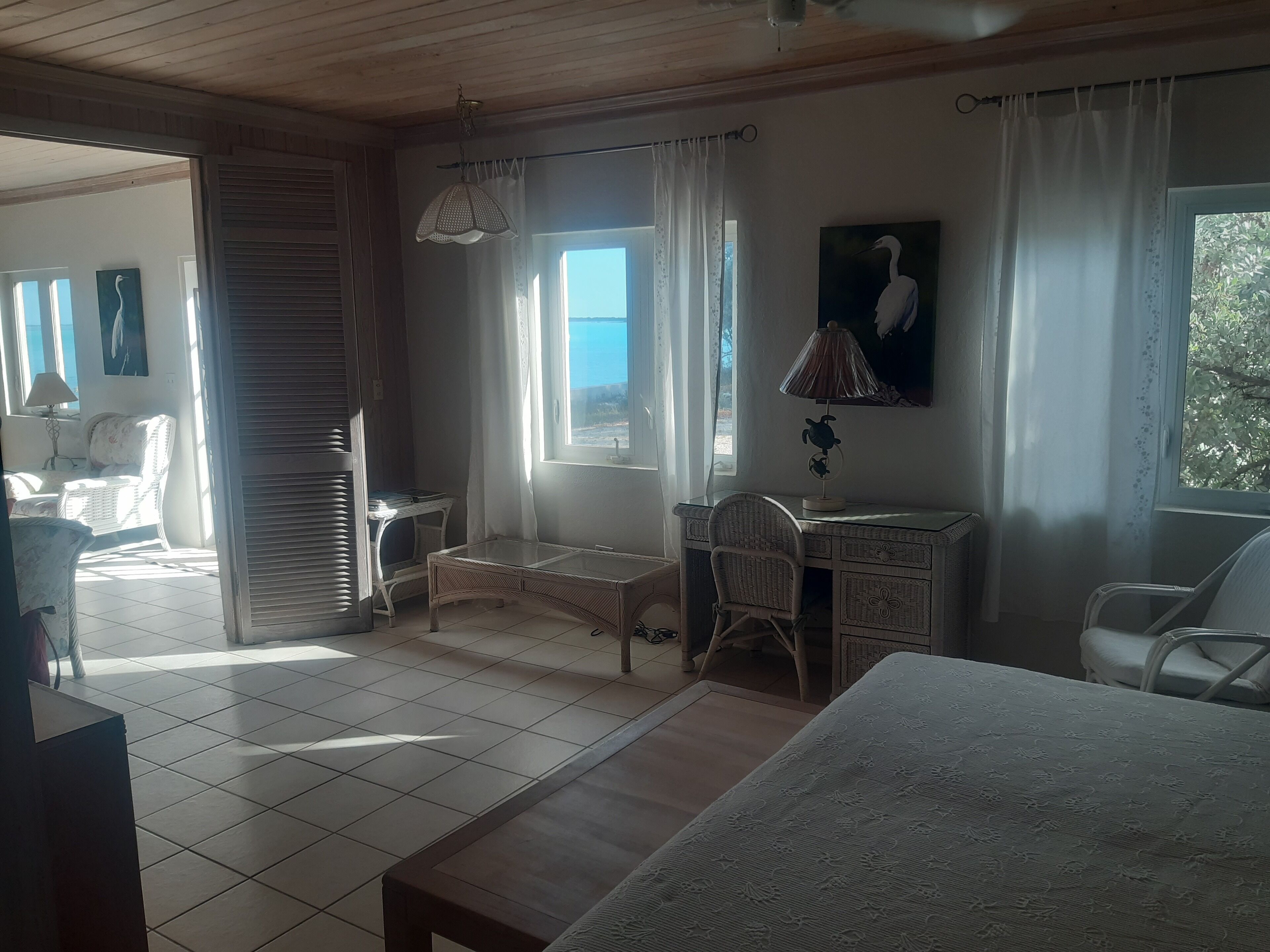 Una habitación con una cama, un escritorio y una silla. Hay una ventana con cortinas, una lámpara y un cuadro en la pared.