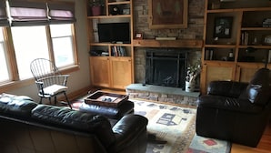 Ein gemütliches Wohnzimmer mit Kamin, Ledersofas und einer Steinwand.