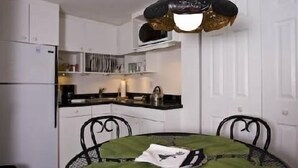 A compact kitchen with white cabinets, a black countertop, and a green tablecloth.