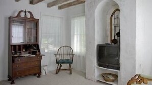 A room with a wooden dresser, a chair, and a television set.