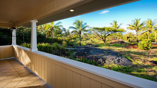A covered outdoor area with a view of a tropical landscape including palm trees and a rocky terrain. - Family Friendly Home, with a Man Cave! (Keaau)