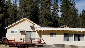 Une cabane à deux étages, dotée d’une antenne parabolique, d’une terrasse avec des chaises et d’un mur en pierre à l’avant.