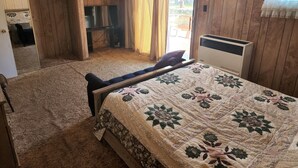 Une chambre à coucher avec un lit, une télévision, une armoire et une fenêtre avec des rideaux.