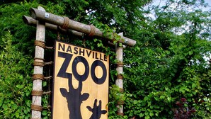 Ein Holzschild des Nashville Zoo mit einer Giraffen-Silhouette und dem Text 'Nashville Zoo at Grassmere'.