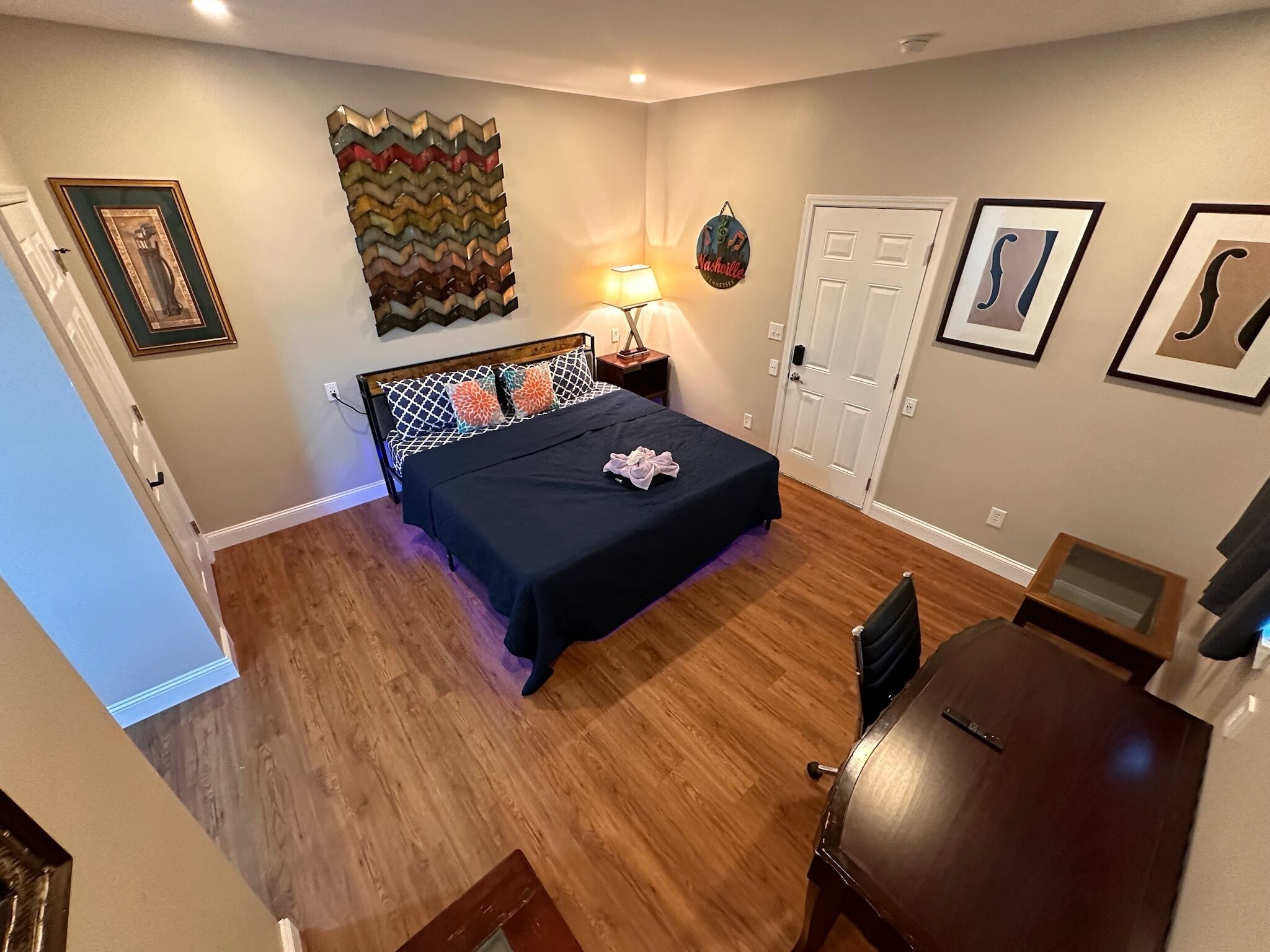 A bedroom with a bed, bedside table, lamp, and a wall decoration.