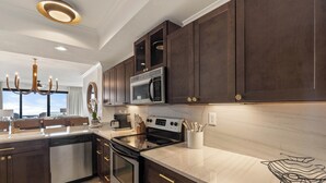 A modern kitchen with dark wood cabinets, stainless steel appliances, and a marble countertop. - Top Rental at SEACHASE!!! Totally remodeled!!! (Orange Beach)