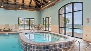 An indoor swimming pool with a view of the ocean, surrounded by lounge chairs and a tiled floor. - Top Rental at SEACHASE!!! Totally remodeled!!! (Orange Beach)