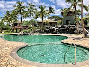 A resort pool with clear water, surrounded by palm trees and a stone deck. - Private, Peaceful, Perfect! (Waimea)