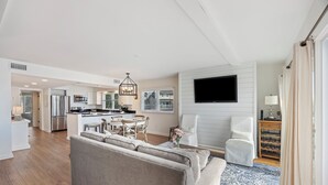 A modern living room with a sofa, a dining area, and a kitchen in the background.