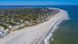 An aerial view of a coastal residential area with houses along the beach and a clear view of the ocean.